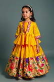 Young girl wearing a traditional yellow and multicolored dress with floral patterns on a gray background                                by best fashion designer in pune