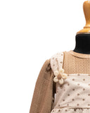 Mannequin wearing a beige sweater with a white dress featuring floral patterns on a white background by fashion designers in pune