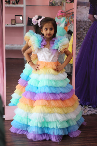Child wearing a colorful dress with a rainbow skirt in front of a mirror by fashion designers in pune