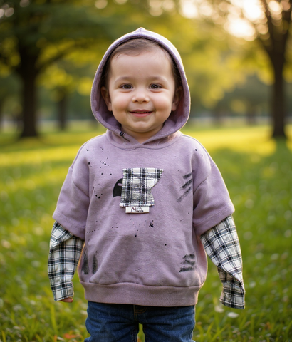 Child wearing a purple hoodie with a plaid design in a park setting by aura fashionista